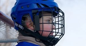 A boy plays hockey on the outdoor ice area. Boy seven years.